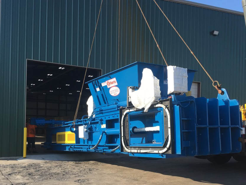 Moving a two-ram baler by crane into a building for installation